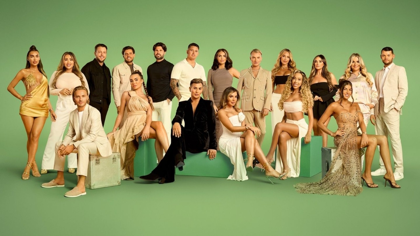 Promotional cast image for a reality TV series featuring a large group of contestants posed against a green studio backdrop. The cast wear coordinated neutral and gold-toned outfits, with some standing and others seated in a formal ensemble portrait.