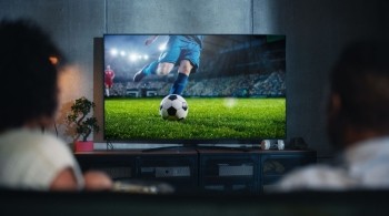 Two people watching a football match on their TV