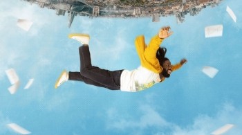 Upside down image of a man with a yellow jacket falling from a city into the sky. Key art for Dreaming Whilst Black.