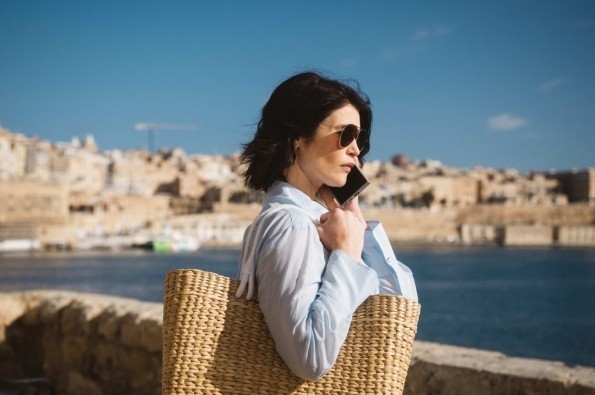 Intelligence officer holding a woven bag while standing by the waterfront in a European city, featured in Secret Service