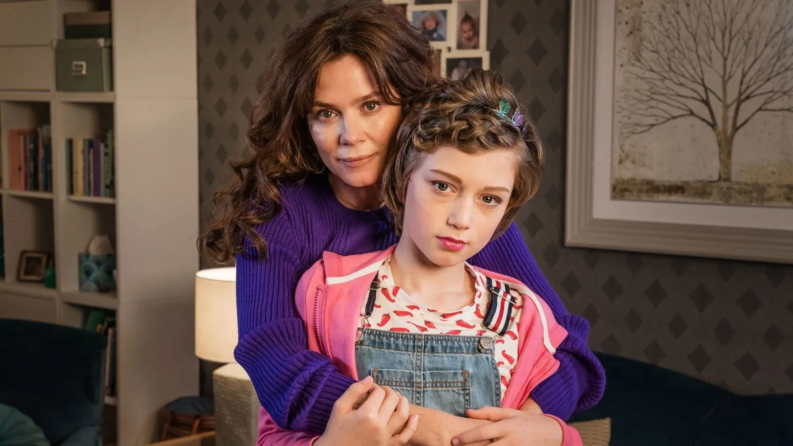 A women holding her daughter, both with brown hair in a living room
