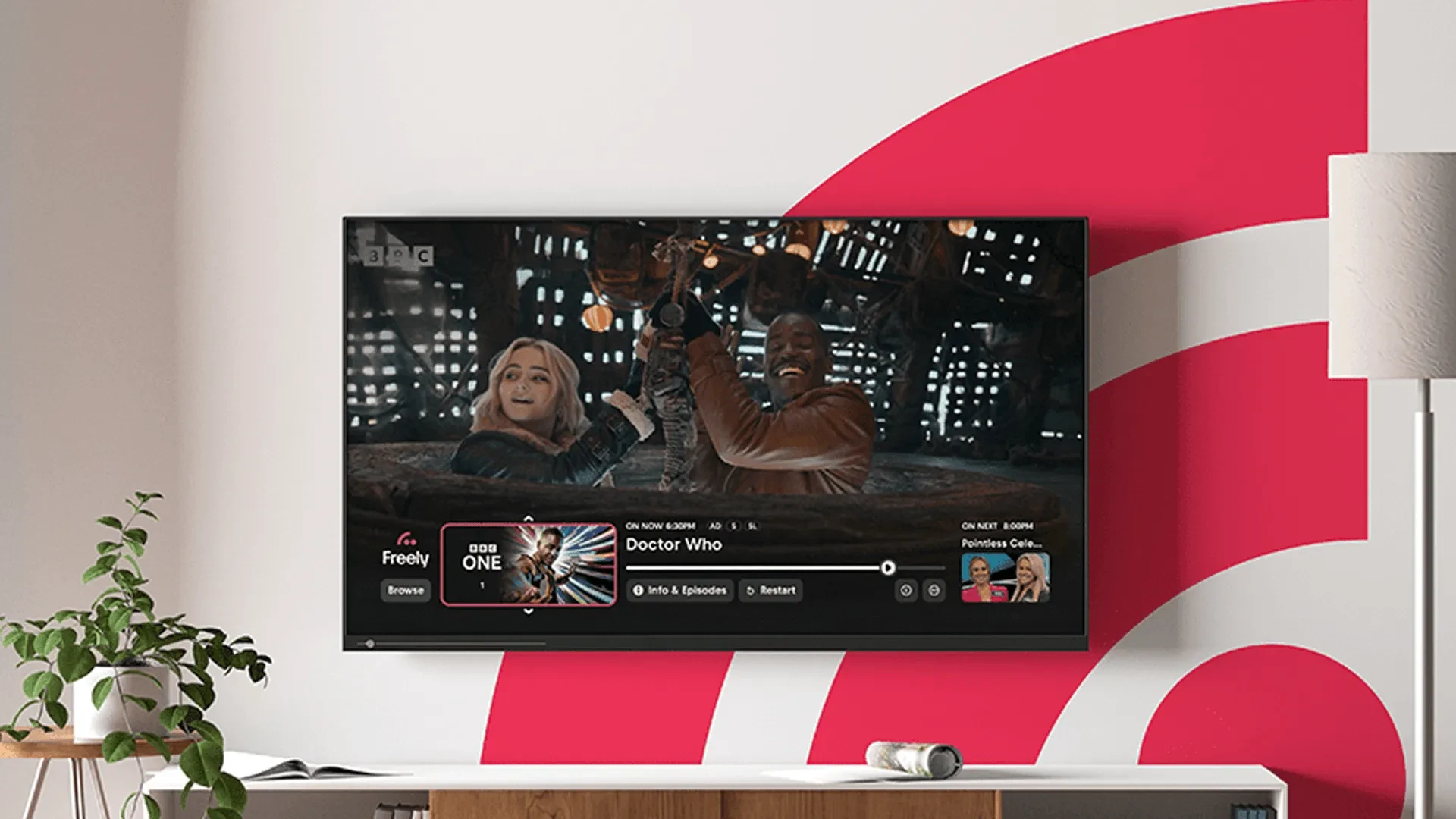 A promotional image for the streaming service Freely shown on a wall-mounted television. On the screen, Millie Gibson as Ruby Sunday and Ncuti Gatwa as the Fifteenth Doctor are laughing together in a scene from Doctor Who