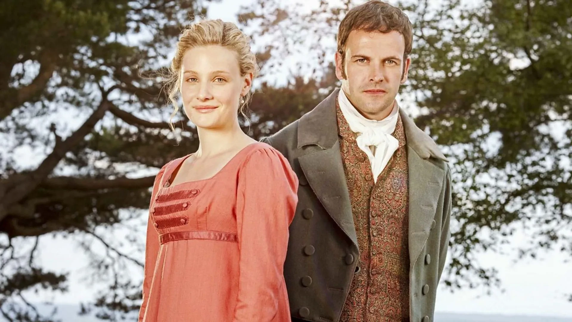 Three women in Regency-era dresses stand on a coastal hillside with waves and a cottage behind them; promotional image for the 2009 TV adaptation of Emma.