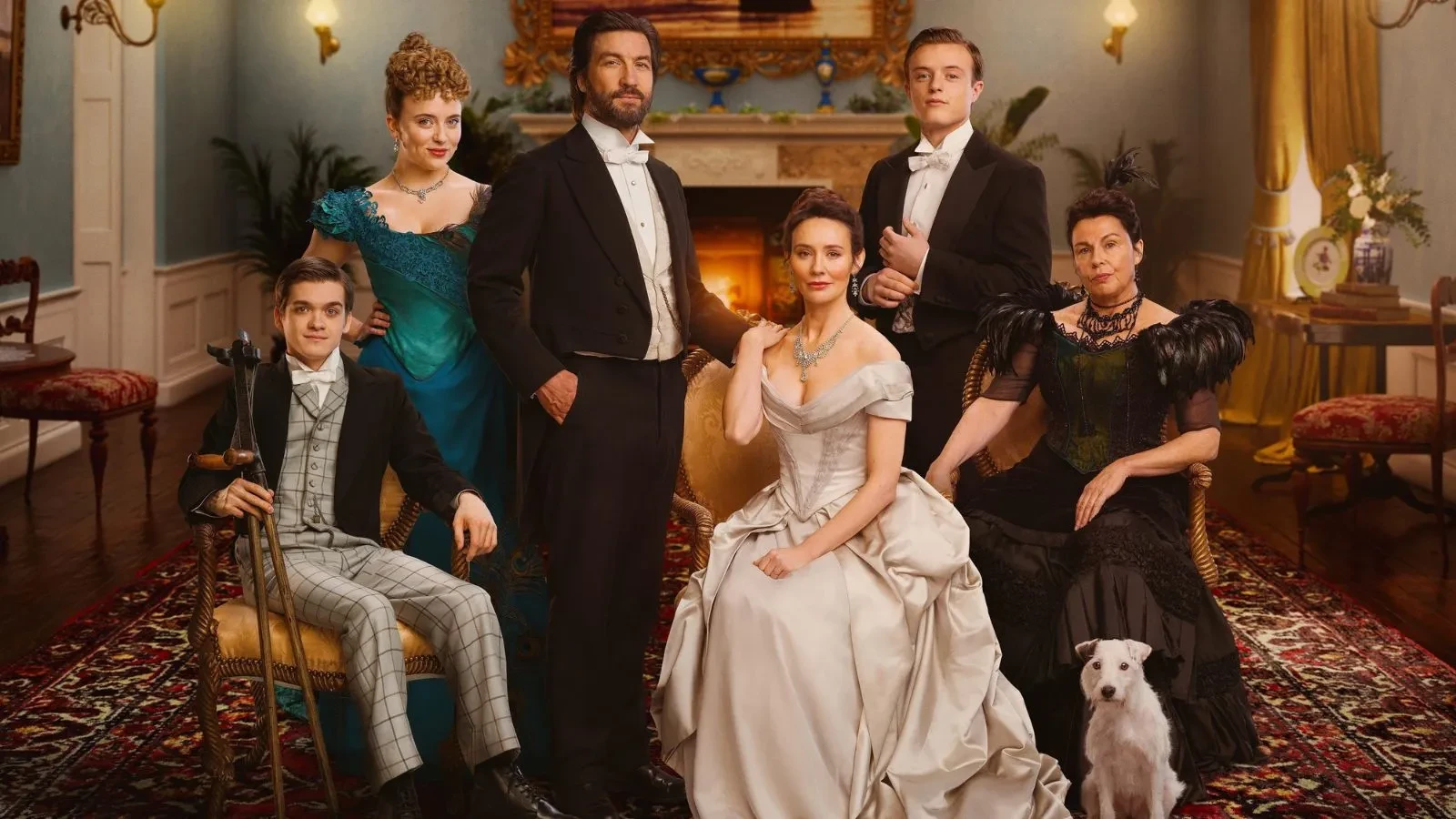 Promotional image from season 2 of the British drama series The Hardacres, showing five people dressed in elegant period clothing posed in a richly decorated room with a fireplace, ornate furniture, and a patterned rug. A white dog sits in the foreground.