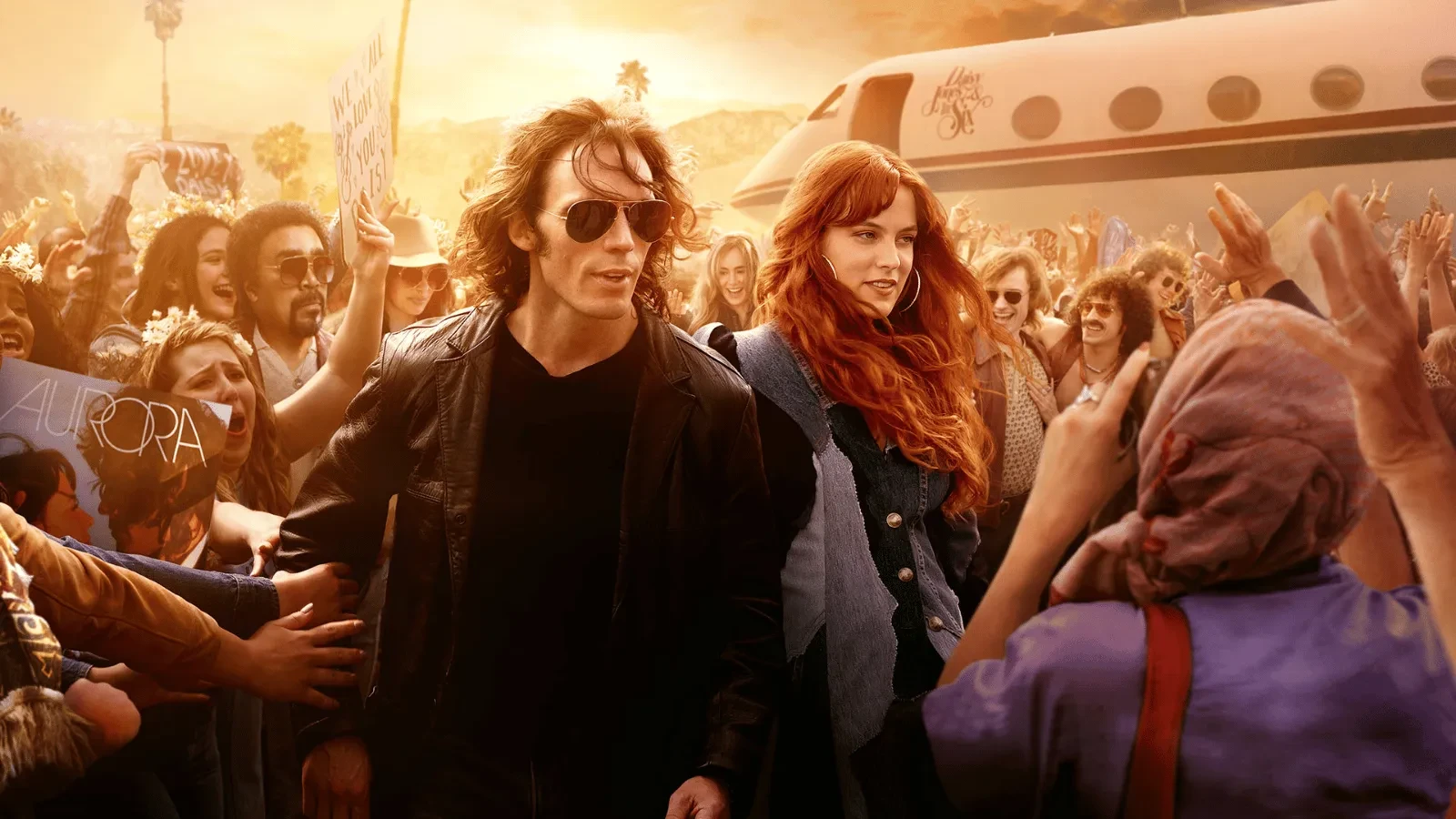 A man and a woman rushing to get onto a private jet with fans surrounding them