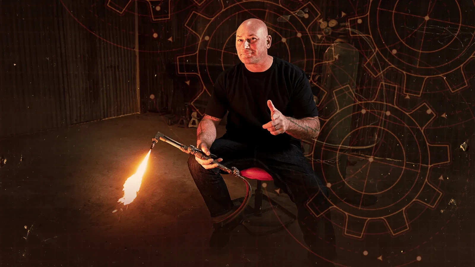 A custom builder sits in a workshop holding a flaming blowtorch, sparks flying as bold mechanical graphics glow in the background. 