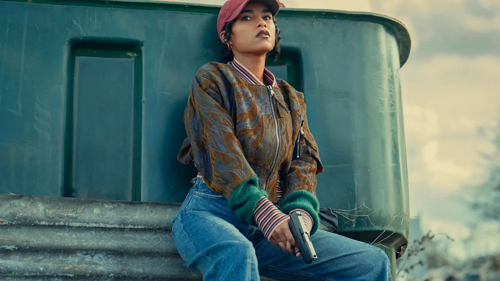 Promotional image for Hit Point featuring a central character seated outdoors beside an industrial structure while holding a handgun, highlighting the action thriller's crime, danger and suspense themes.