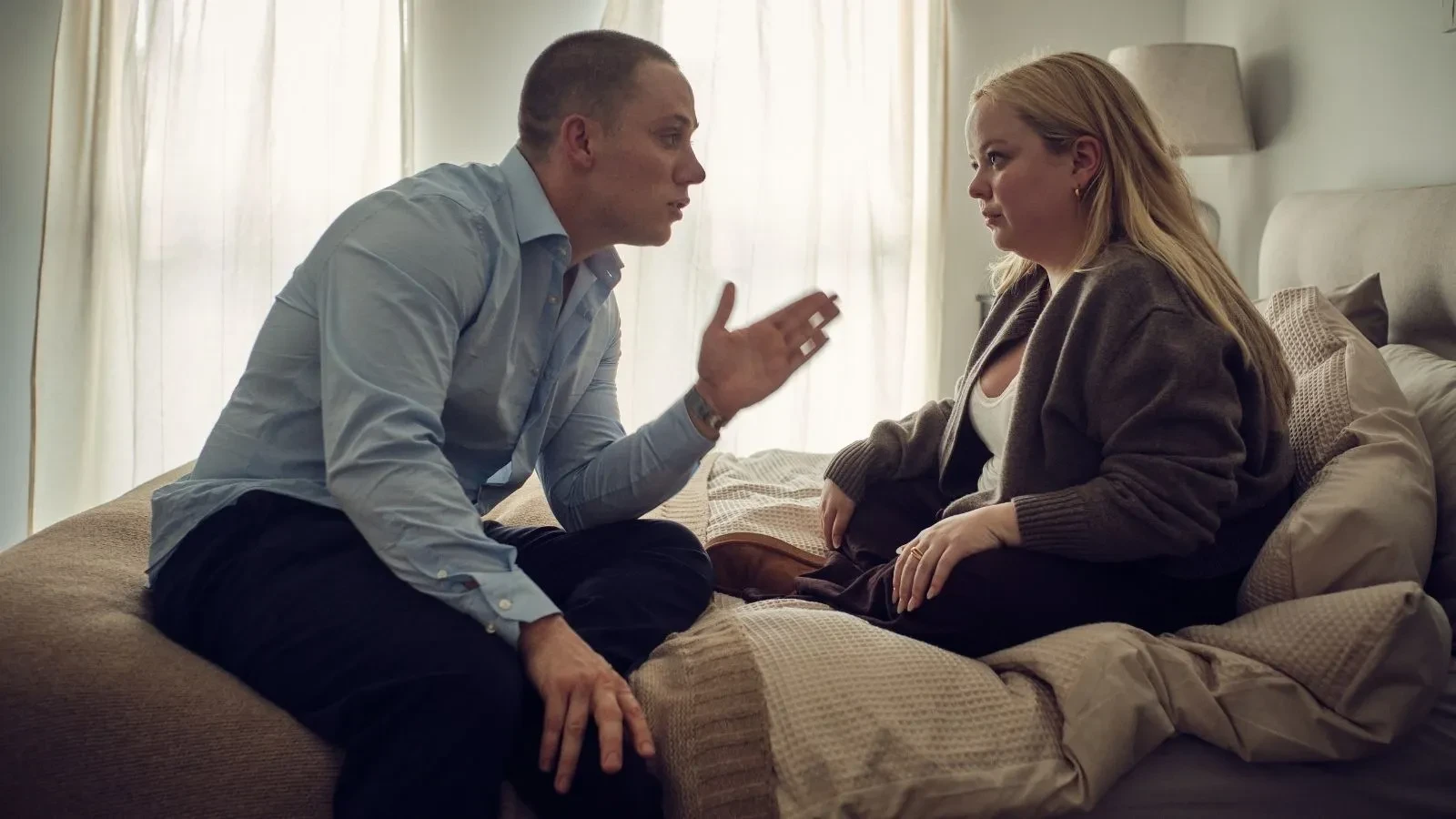 I Am Helen promotional image featuring two people sitting on a bed in a softly lit bedroom, engaged in an intense conversation, highlighting themes of personal relationships, emotional conflict and contemporary drama.