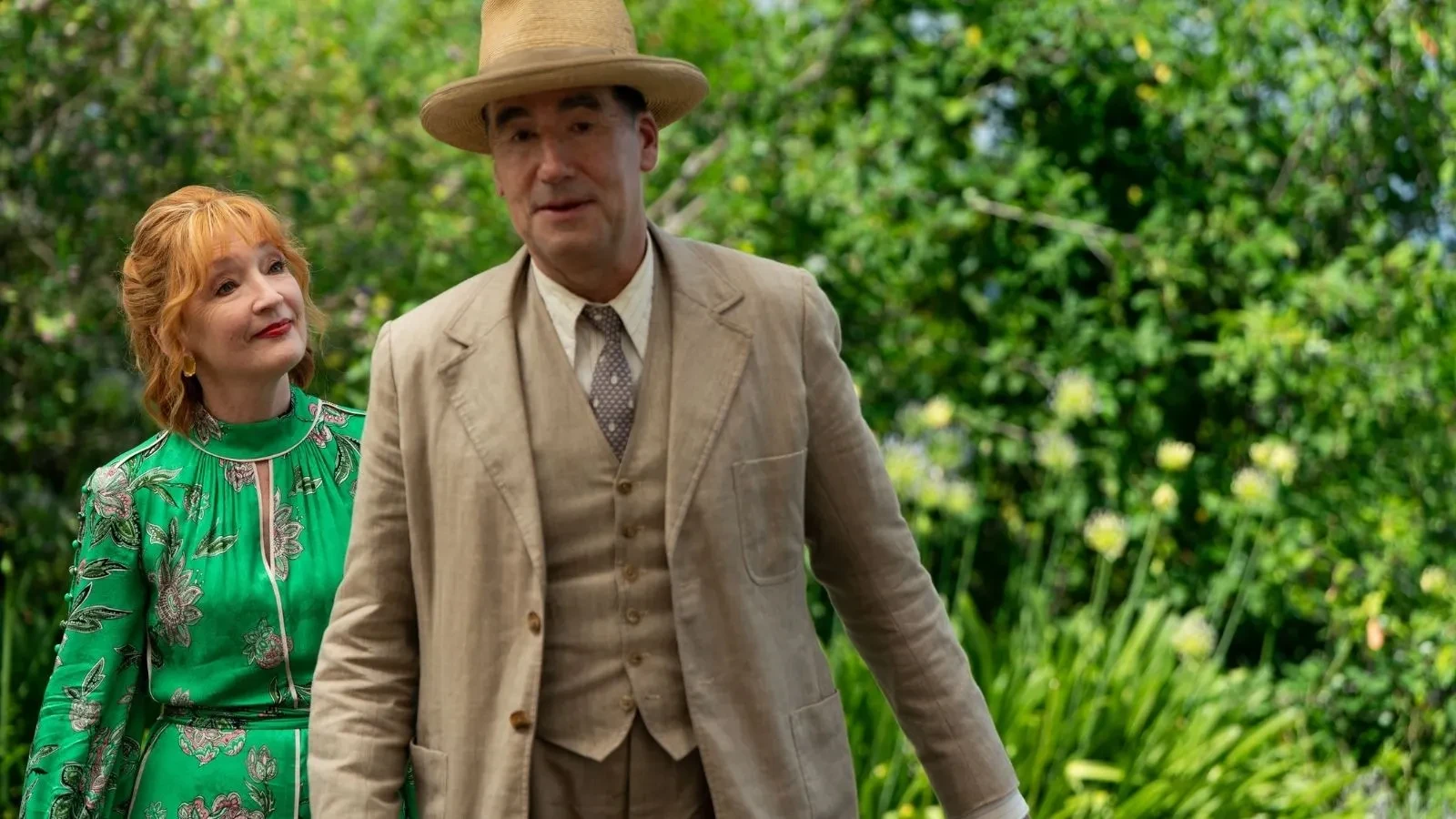 Copilot said: Marble Hall Murders promotional image featuring two characters in vintage-inspired clothing walking through a lush garden setting, with one wearing a tailored suit and wide-brimmed hat, highlighting themes of mystery, investigation and classic period drama in an elegant countryside environment.