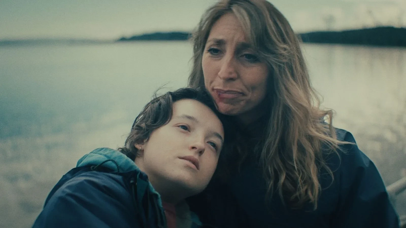 Copilot said: Maya promotional image featuring two people seated beside a calm waterfront, with one resting against the other, set against a muted coastal backdrop, highlighting themes of family relationships, resilience, personal struggle and emotional drama in a contemporary setting.