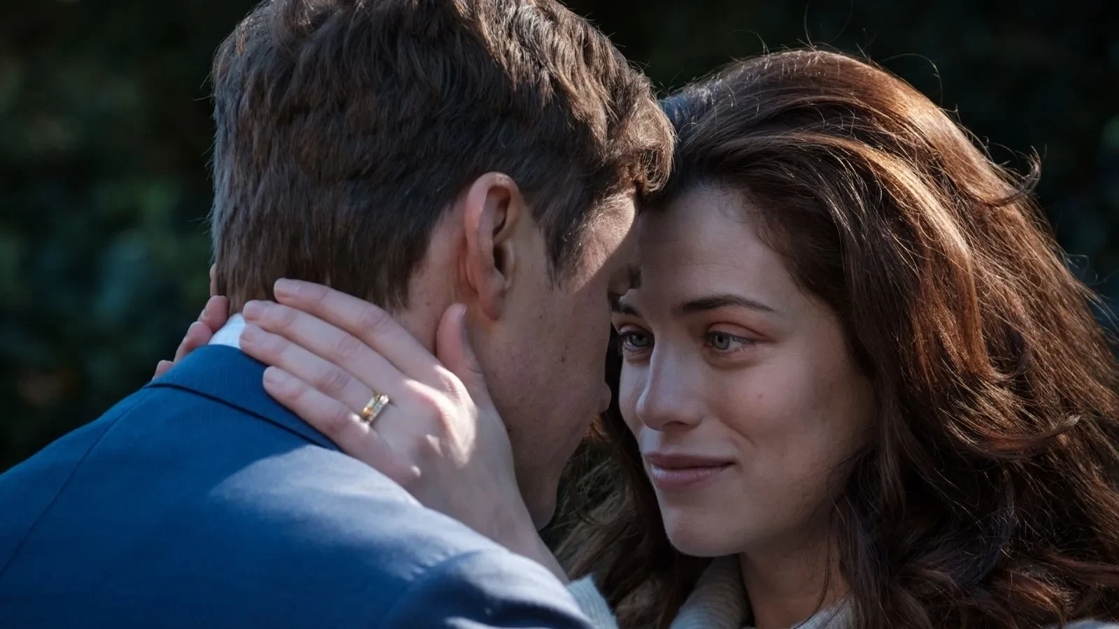 A brunette woman with her head against her husbands staring at him lovingly in the drama The Secret She Keeps
