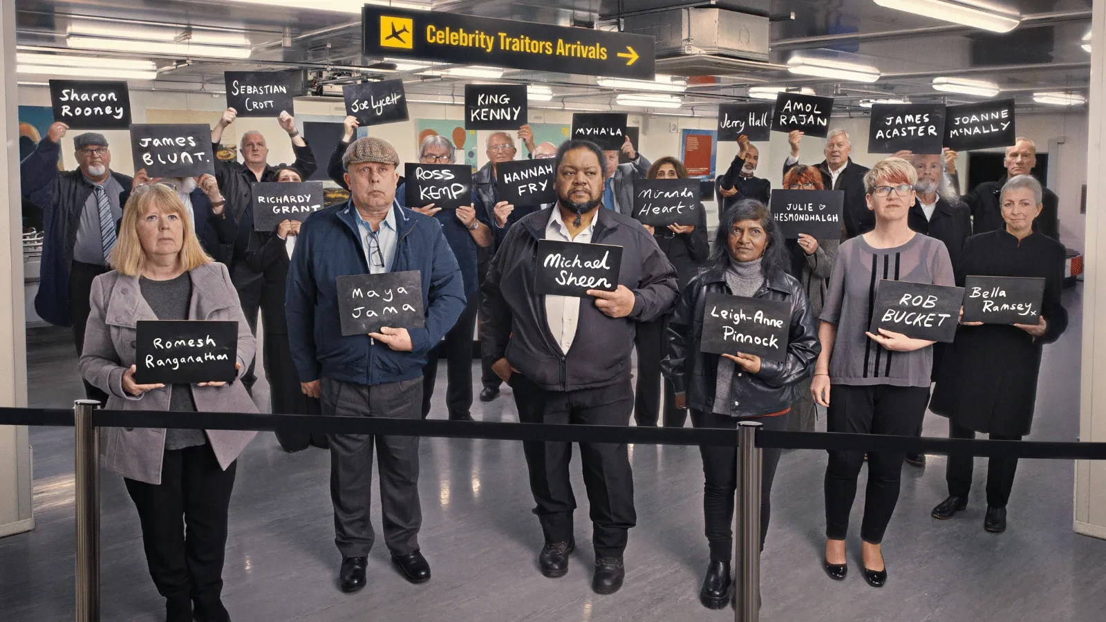 Contestants gather beneath a "Celebrity Traitors Arrivals" sign, holding boards featuring the names of the show's celebrity cast. The promotional image is styled like an airport arrivals area and hints at the mystery and deception of the series.