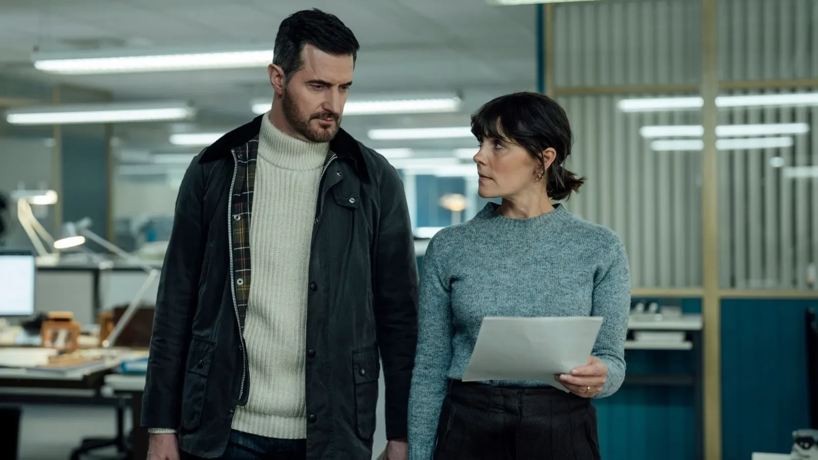 Richard Armitage and Annabel Scholey wearing dark clothing in an office space in the drama Winter