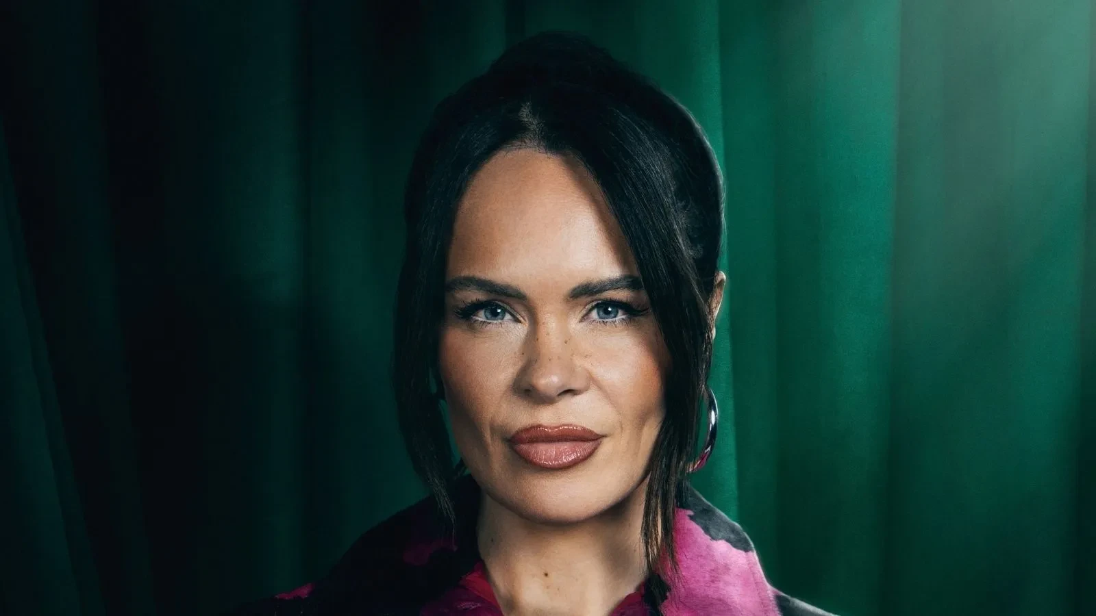 Joanna McNally stood against a green backdrop in Celebrity Traitors