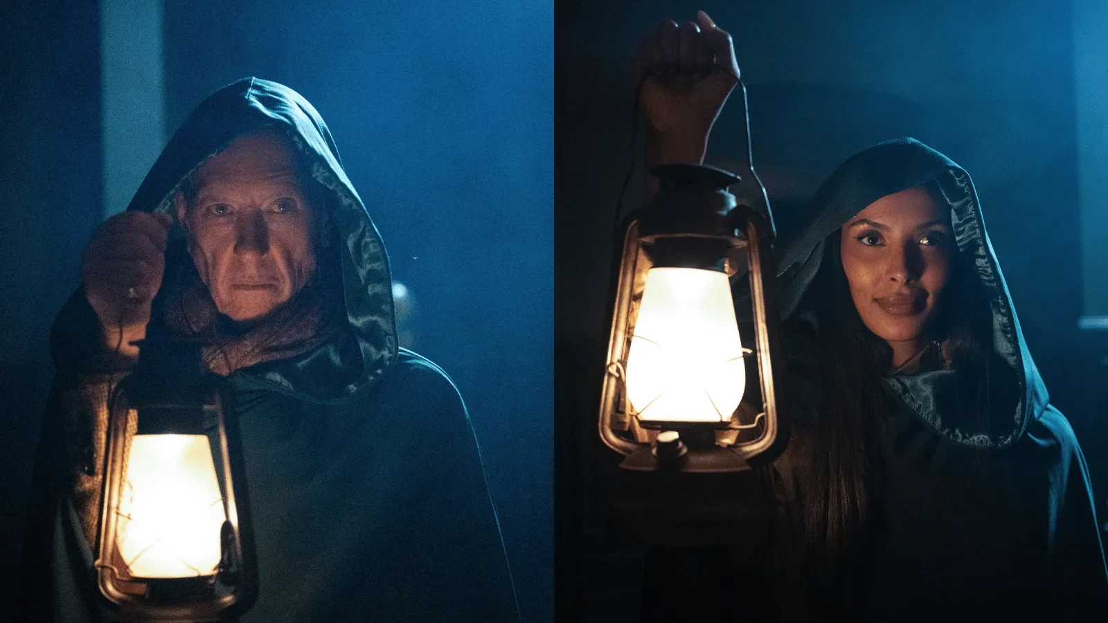 Two hooded figures stand in a dimly lit setting, each holding a glowing lantern. The scene is illuminated by warm lantern light against a dark blue background, creating a dramatic and atmospheric effect.