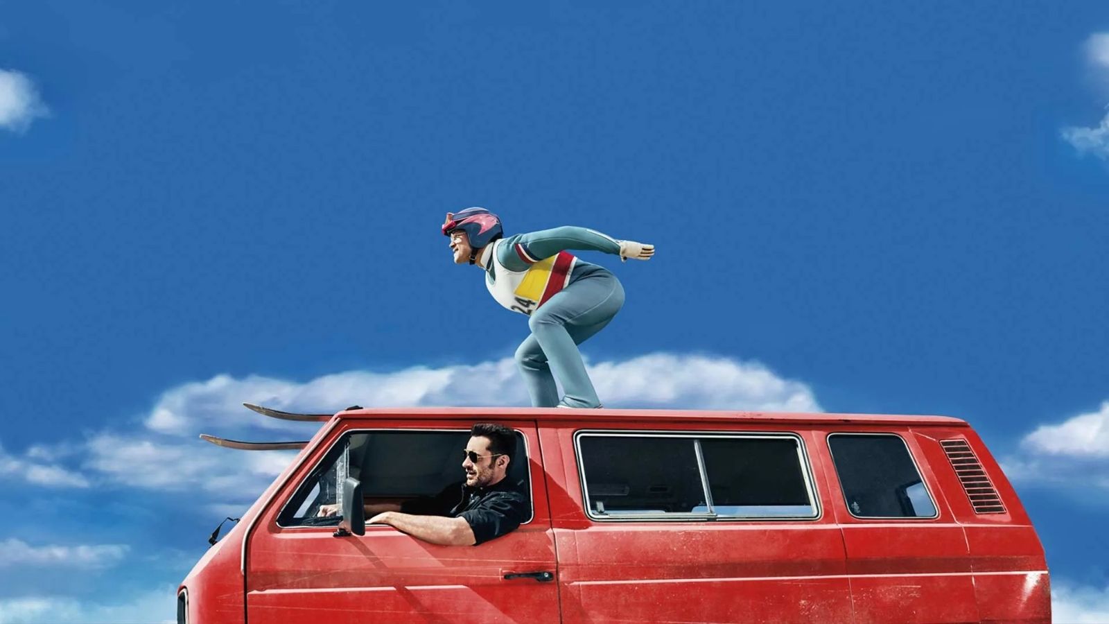 Promotional image featuring a ski jumper in full gear crouched on top of a bright red van under a clear blue sky with scattered clouds, evoking a daring and unconventional sporting moment.