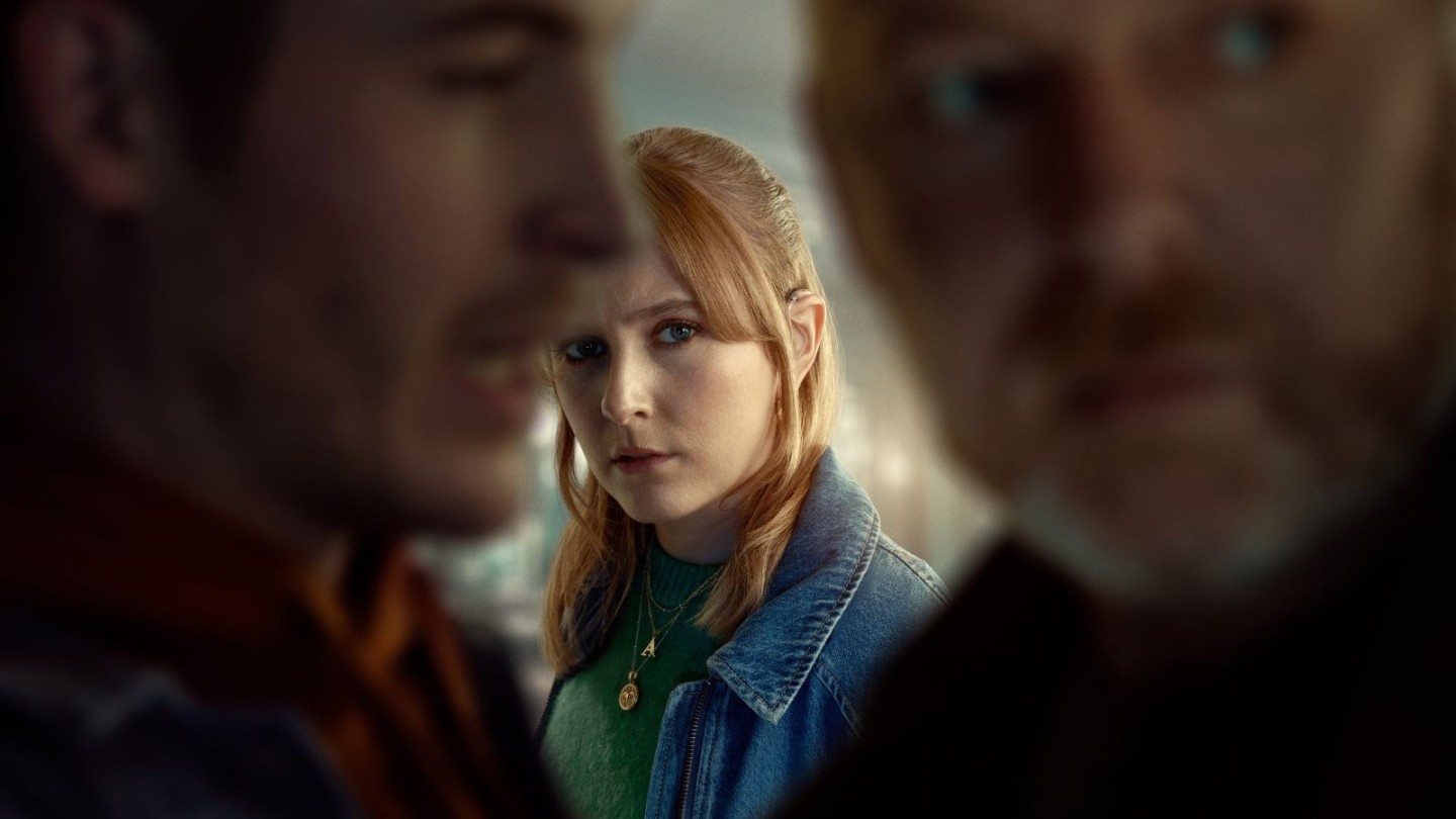 Women stood in the background between two men overhearing their conversation