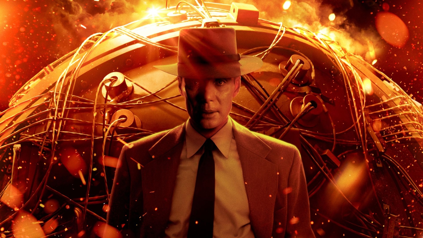 Poster art for the film Oppenheimer, showing a man in a suit and fedora standing before a glowing, fiery backdrop and a complex mechanical device, evoking themes of nuclear science and historical drama.
