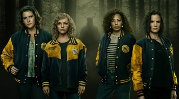 Four people wearing matching yellow-and-blue varsity jackets standing in a dark, misty forest, with a shadowy horned figure looming in the background