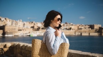 Intelligence officer holding a woven bag while standing by the waterfront in a European city, featured in Secret Service