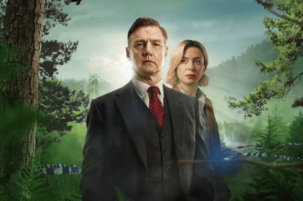 Two individuals in formal clothing standing in a forest clearing with a large bridge and misty hills in the background, creating a mysterious and dramatic atmosphere.