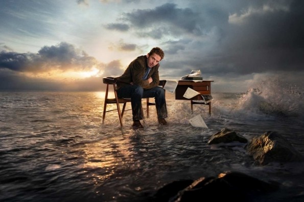 Jim Bergerac sits at a desk surrounded by crashing waves and stormy skies, symbolising inner conflict in the crime drama Bergerac.