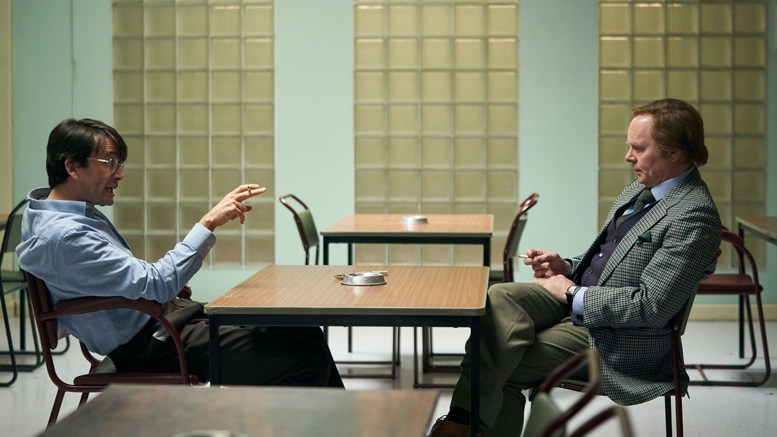 Two men sat at a table across from each other in suits