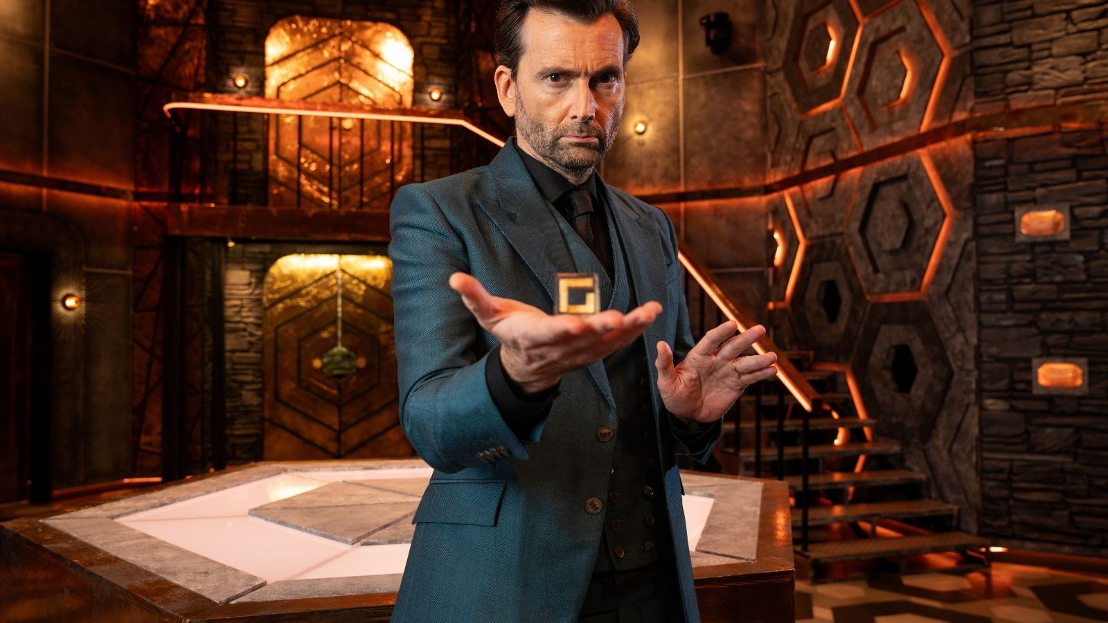 David Tennant holding out his hand in a basement like room