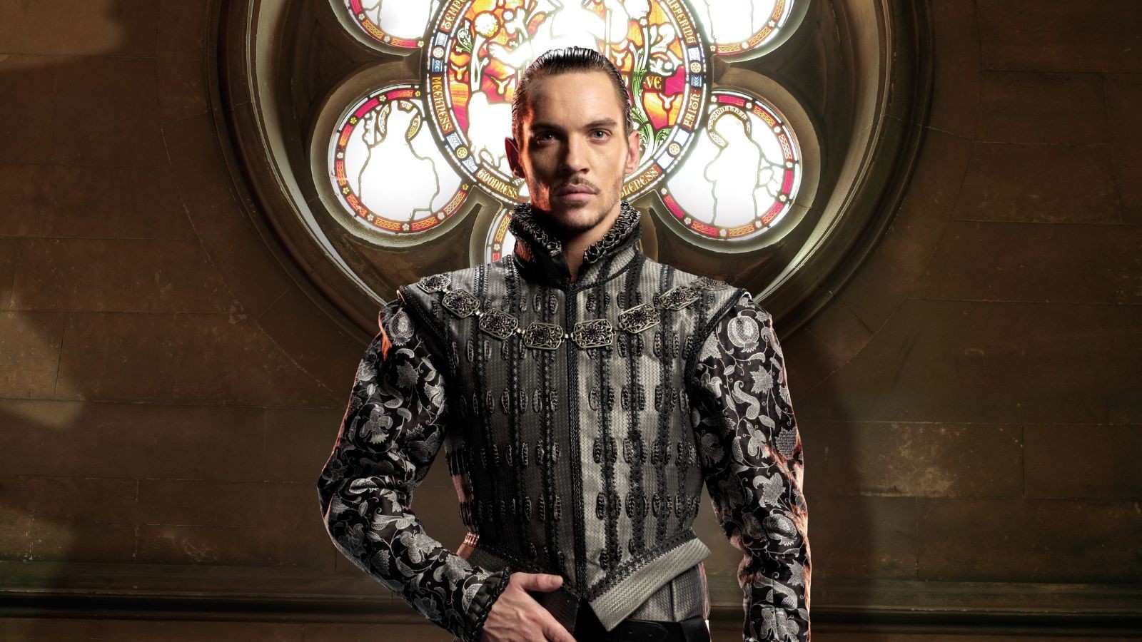 A man wearing royal robes with his right arm in front of his belt