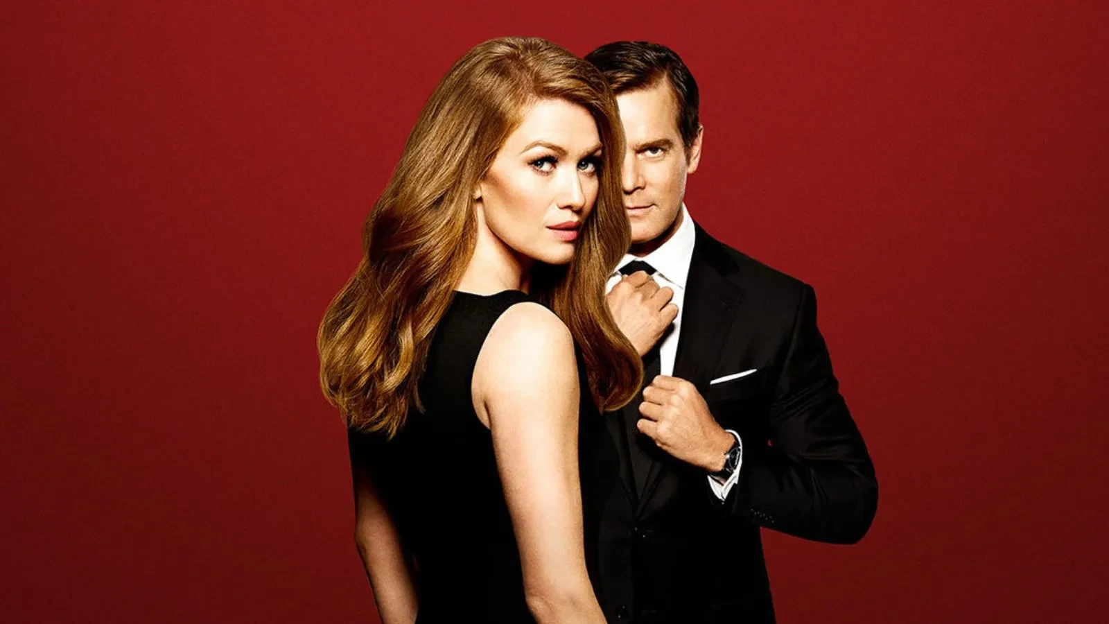 A women with her back to the camera wearing a smart dress stood in front of a man with a suit against a red background