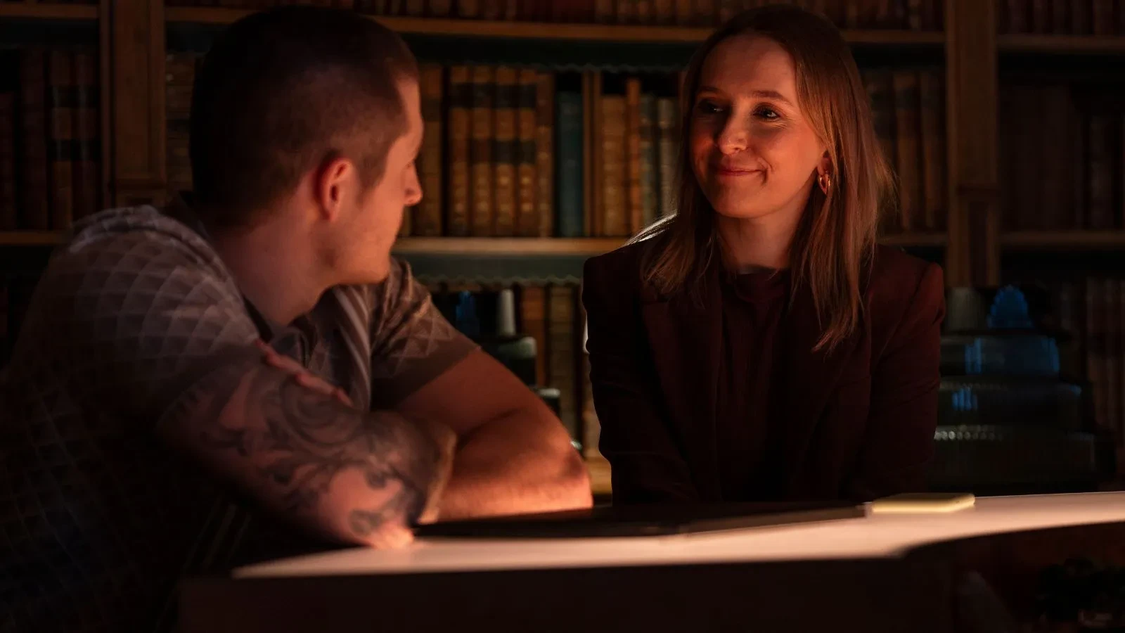 A man and a women sat at a table with books in the background