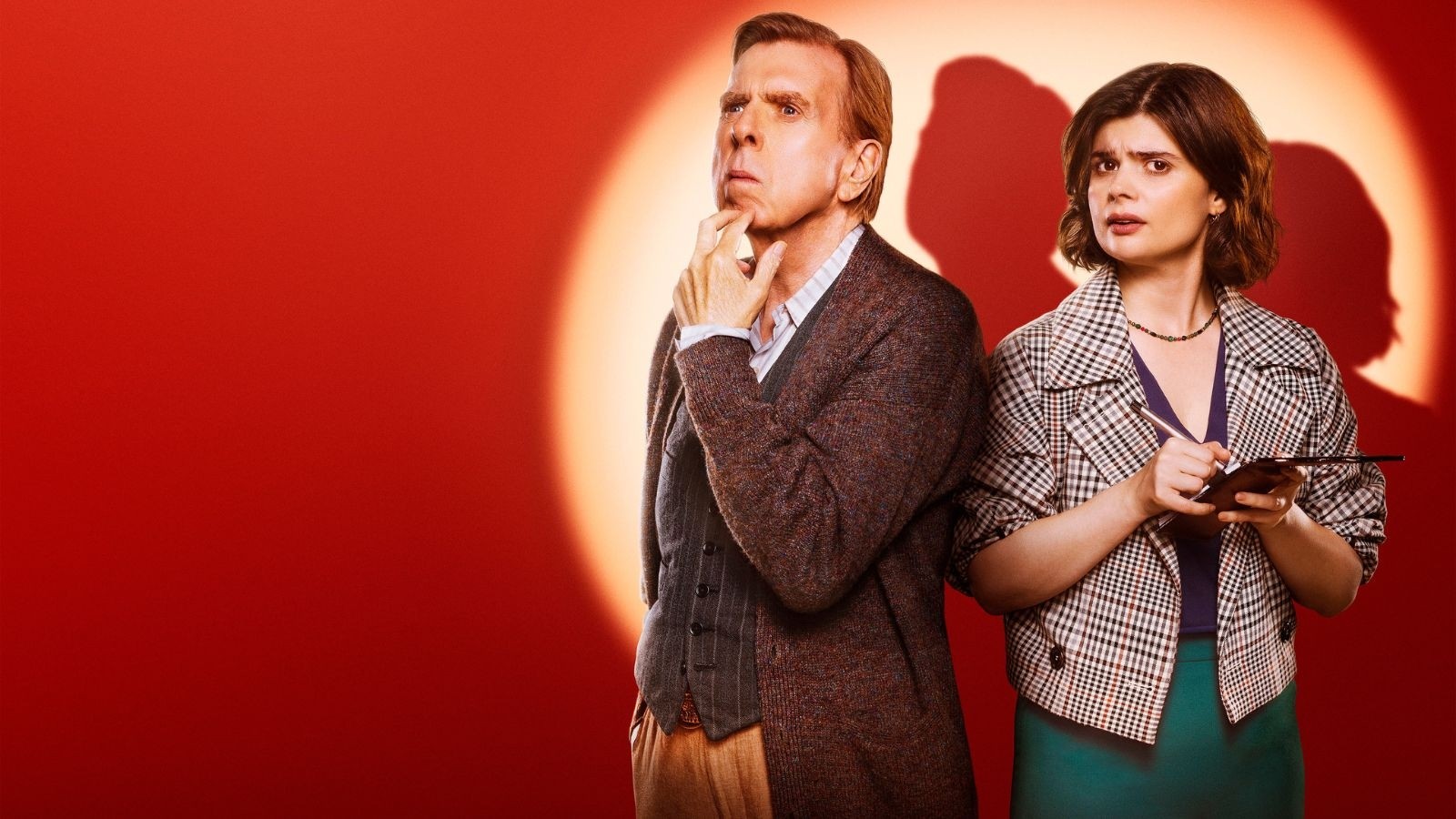 An older man and a younger women against a red background with a spotlight