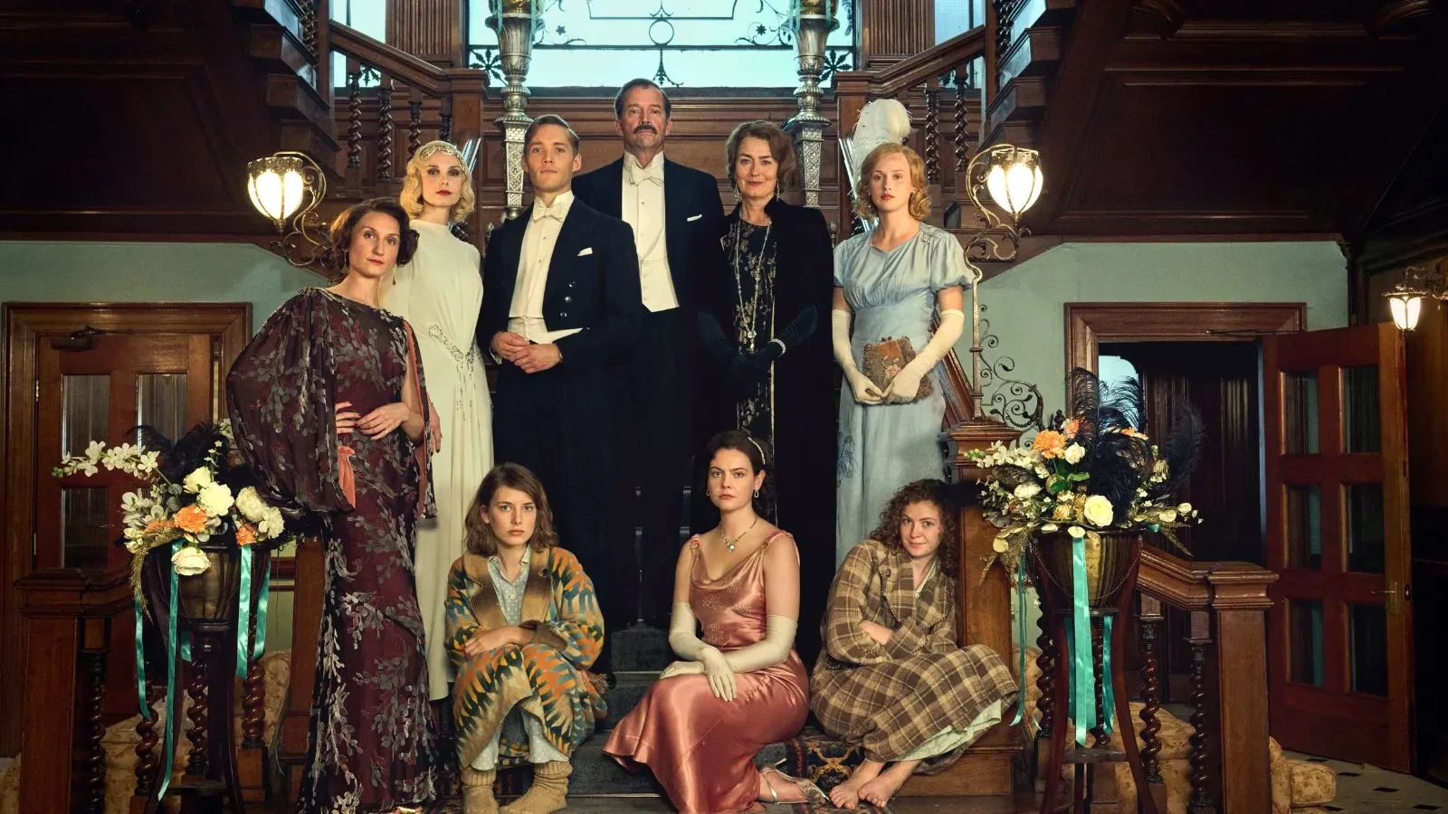 Aristocratic men and women dressed in fine clothing stood on a grand staircase