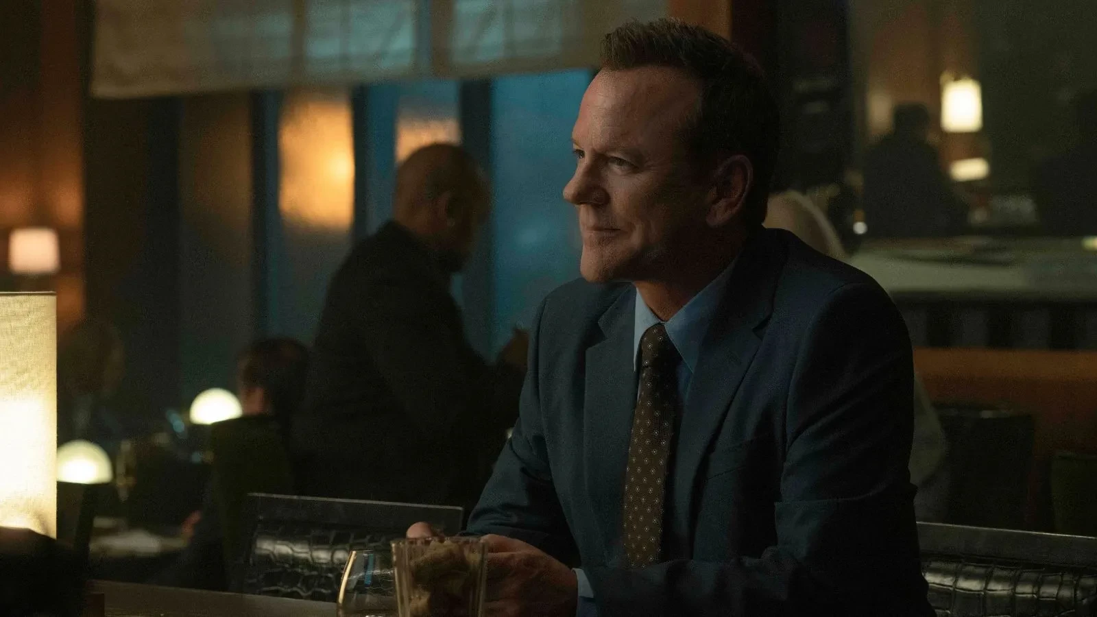 Kiefer Sutherland in a suit in an office