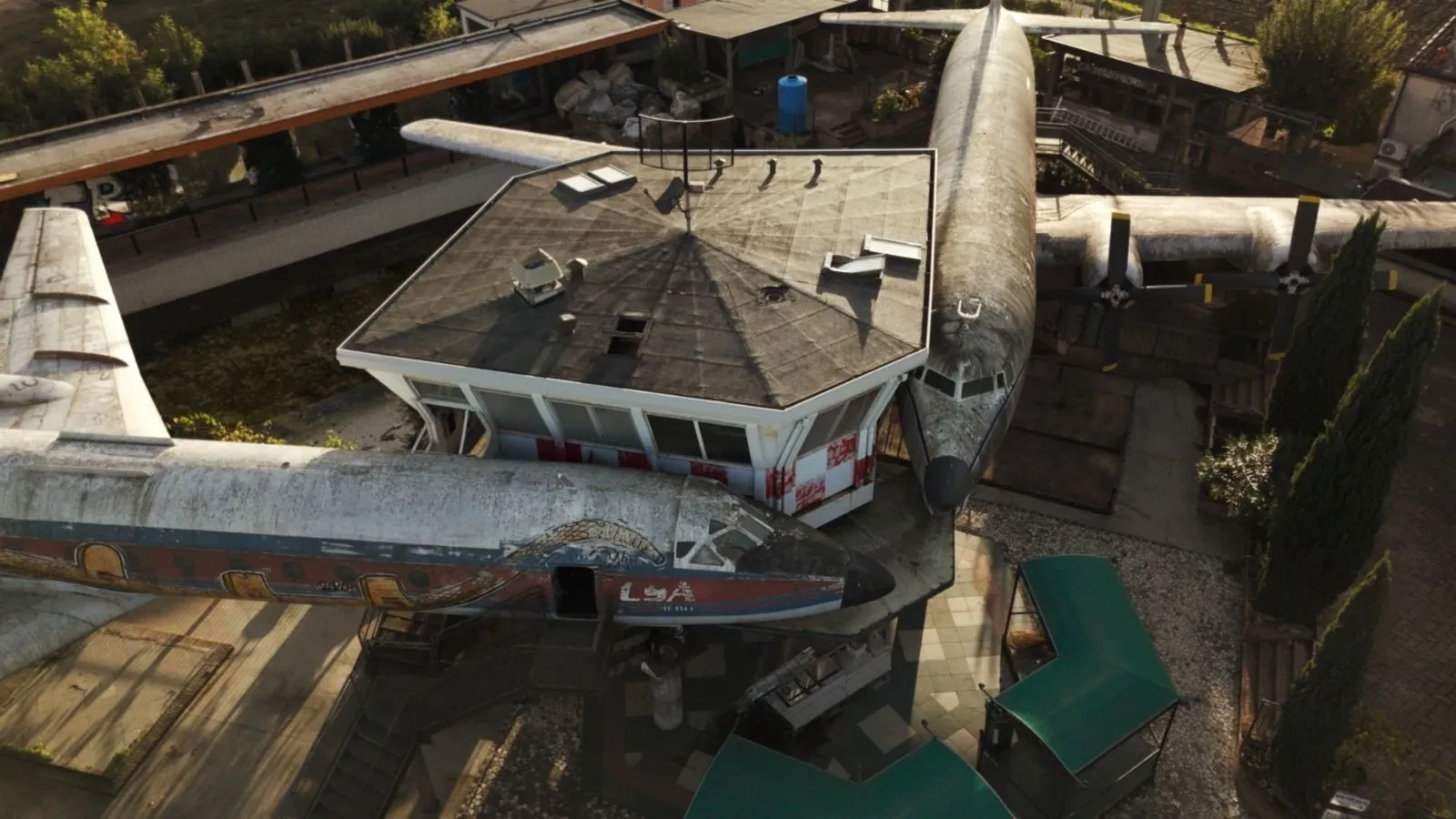 Two abandoned airplanes against an abandoned building
