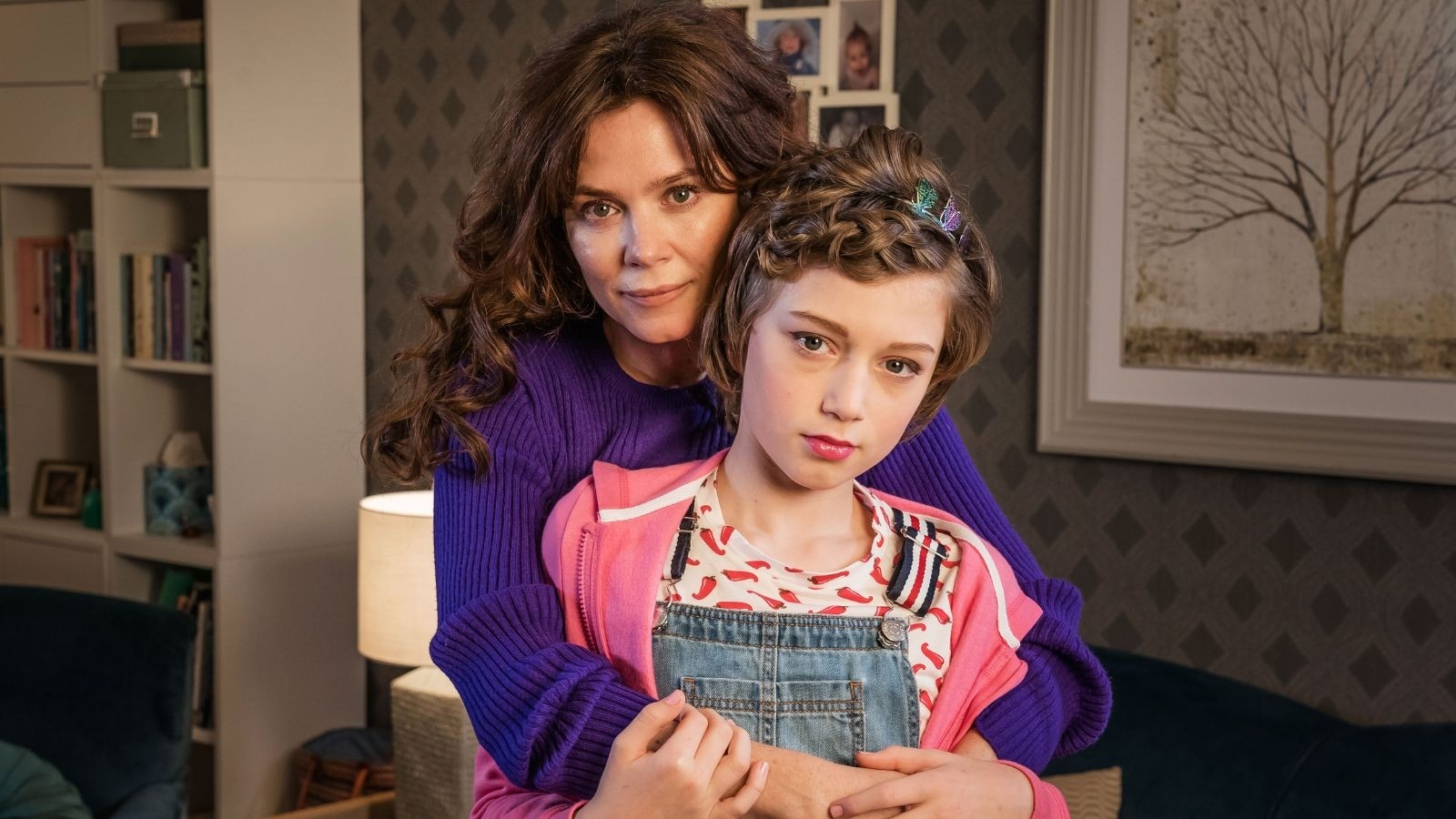 A women holding her daughter, both with brown hair in a living room