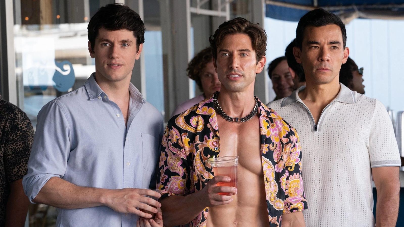 A man with his shirt undone with two young men stood either side of him