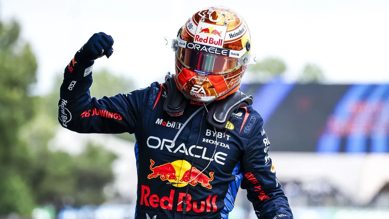 Formula One racer in a blue Red Bull race jacket and a helmet with his arm in the air