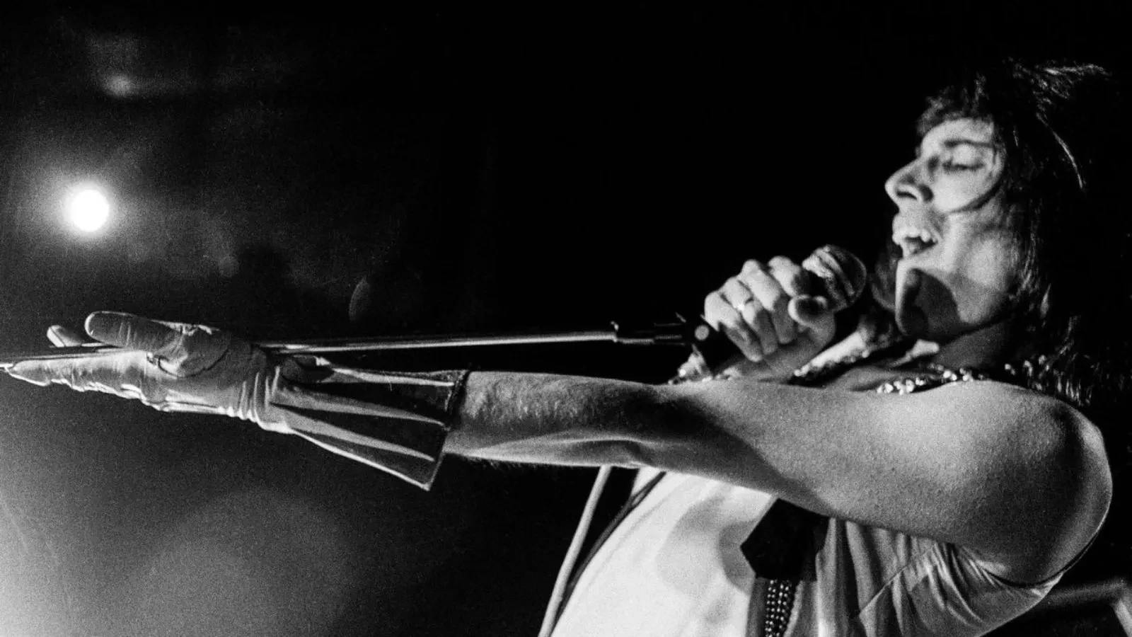 Freedie Mercury with4his arm stretched out singing in black and white