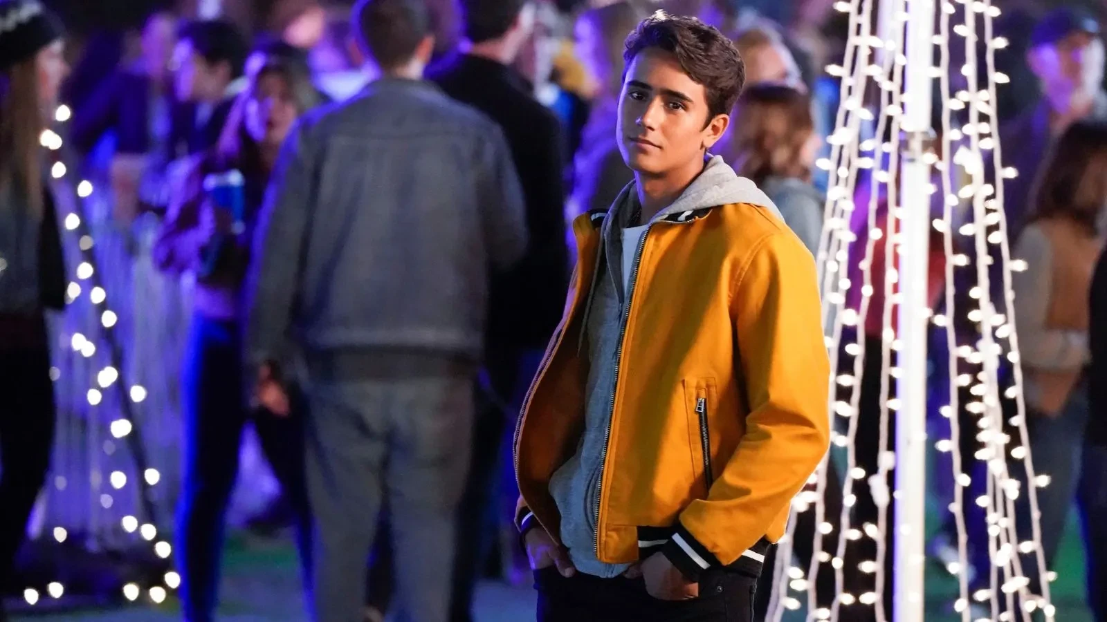 A By in a yellow jacket at what looks like a prom with blue lights