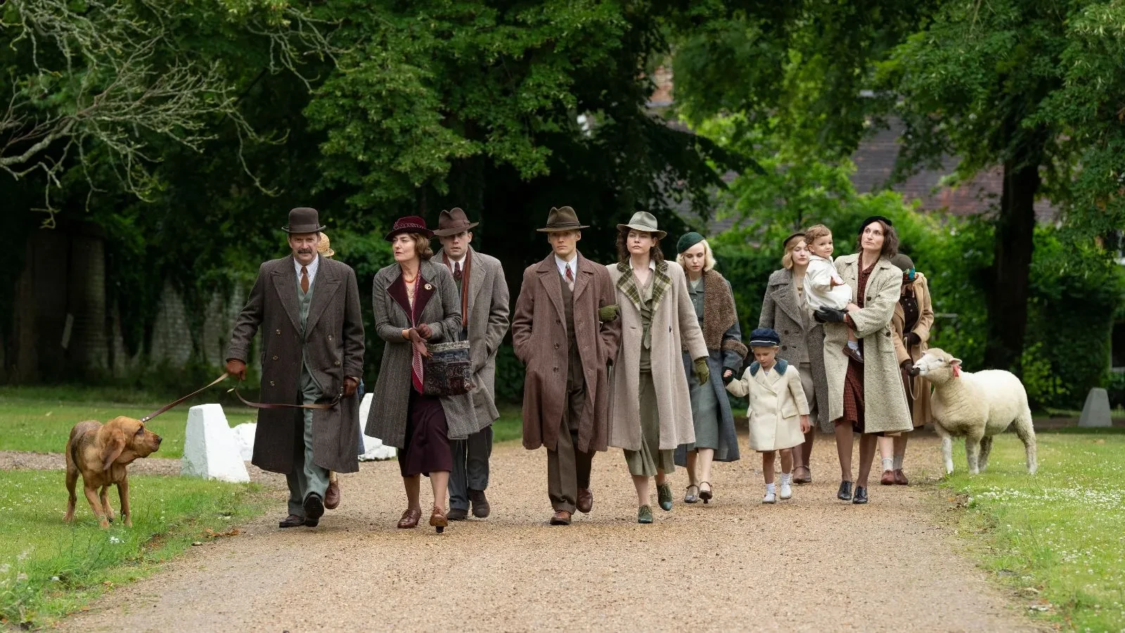 A rich aristocratic family in 1930s clothing walking through church grounds with a dog and a sheep