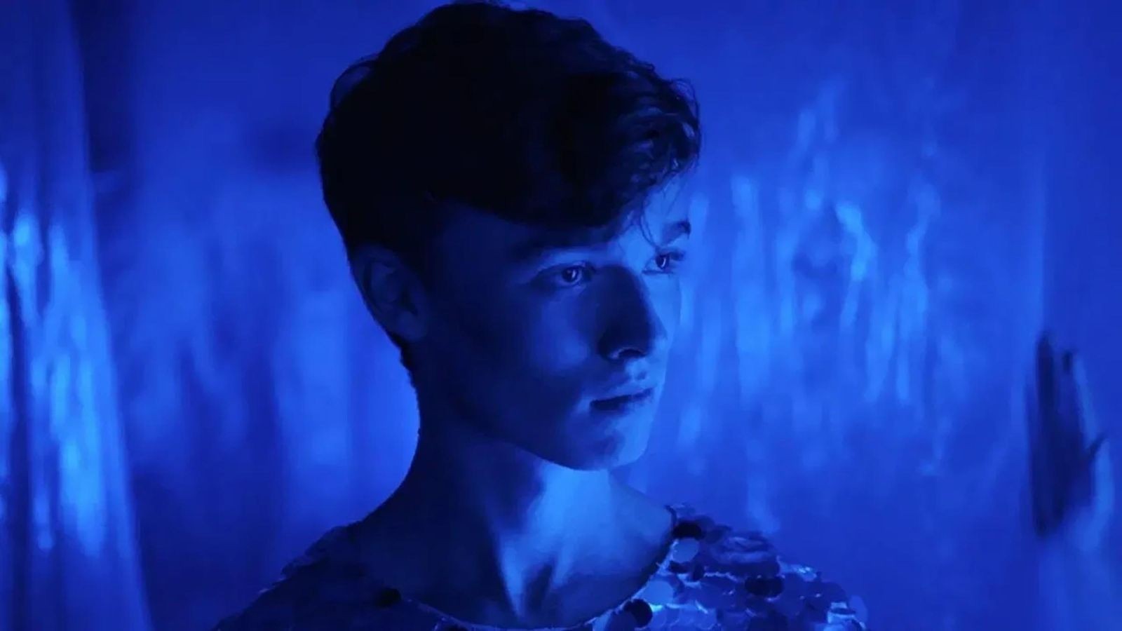 A young man stood in a blue room