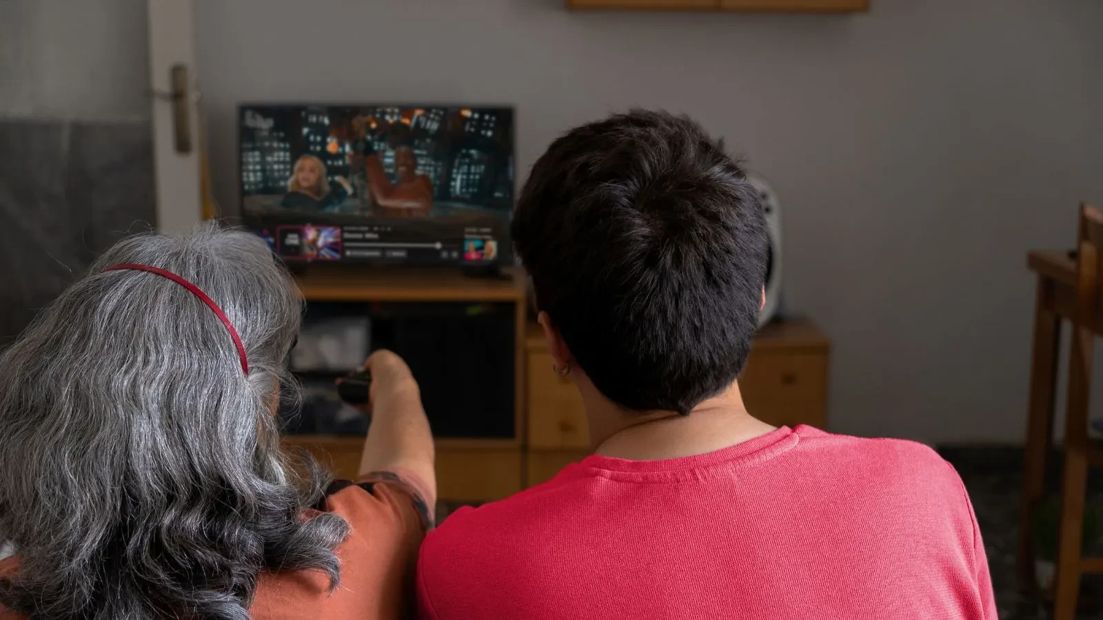 Older women sat next to a younger man in a ink t shirt watching something on tv