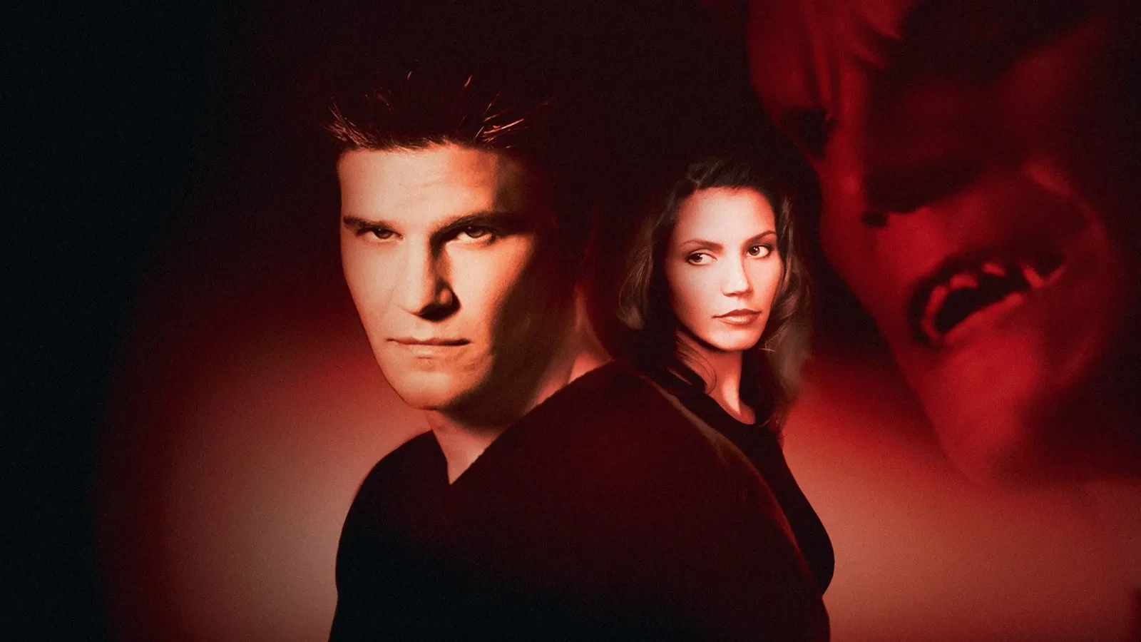 A man wearing a black shirt with a brunette women stood behind him with a red background