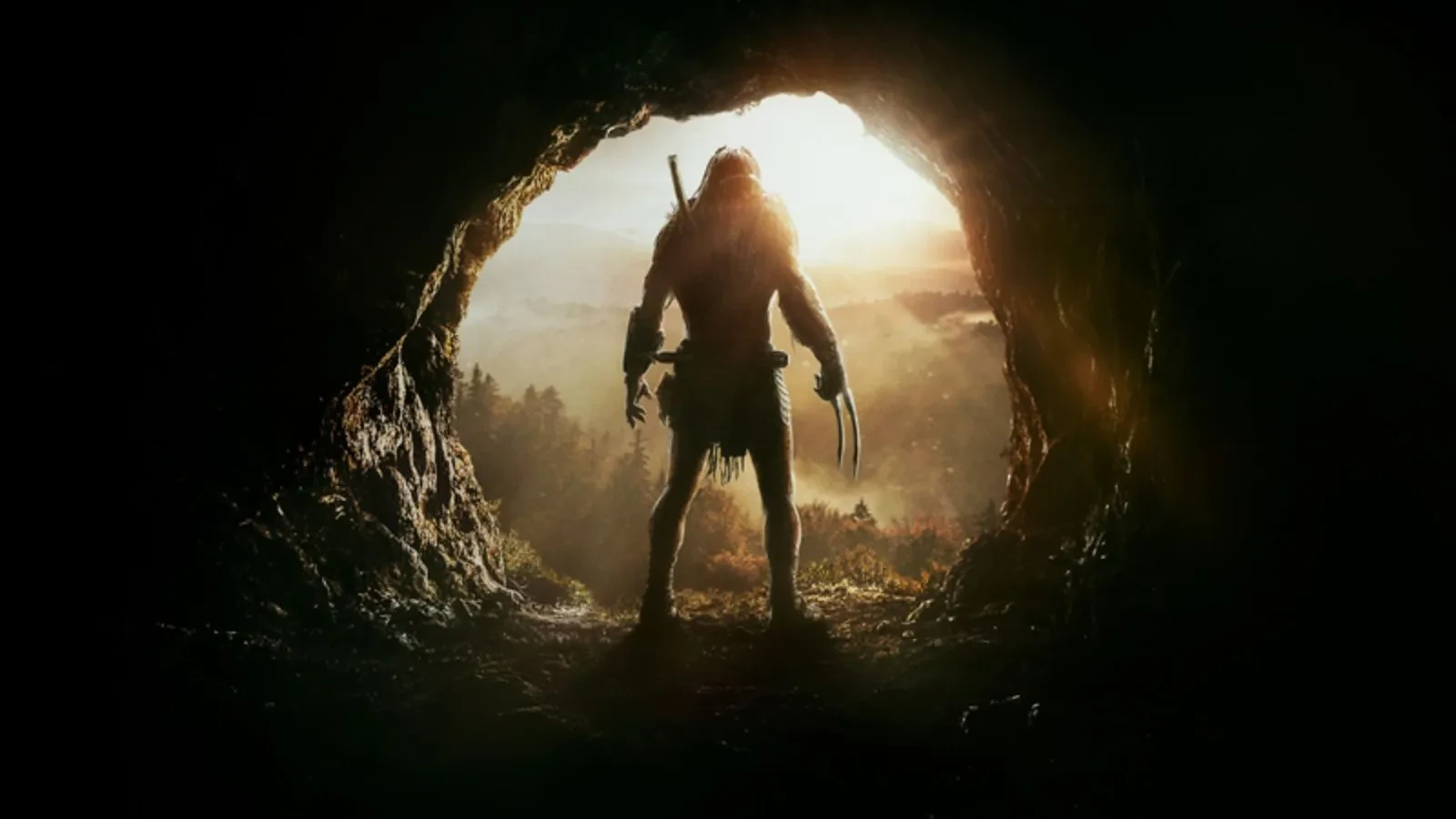 Promotional image for the movie 'Prey'. Silhouetted figure standing at the mouth of a cave, holding a weapon and looking out over a vast forested valley bathed in golden sunlight, creating a dramatic and suspenseful atmosphere.