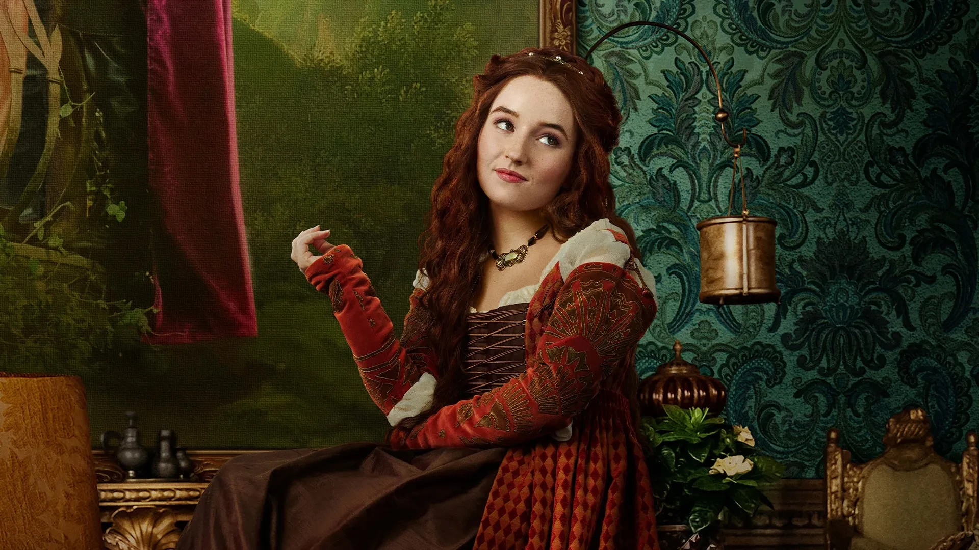 Promotional image for the film Rosaline (2022), showing a woman in elaborate Renaissance-style clothing seated in a richly decorated room with antique furnishings and ornate wallpaper.