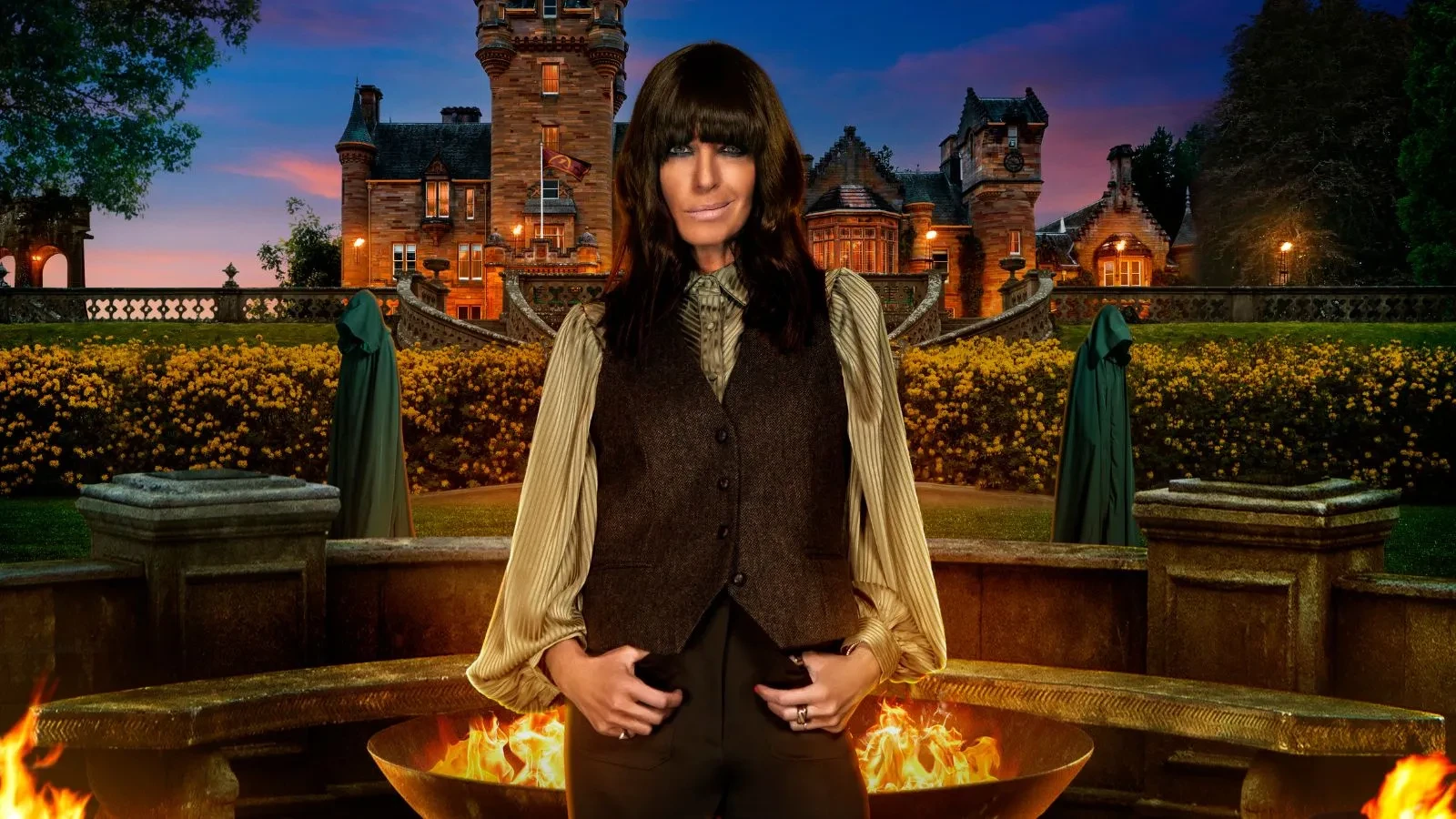 Promotional image from the fourth series of the British reality competition series The Traitors, showing host Claudia Winkleman standing in front of a large stone firepit with flames. Behind her is a grand castle surrounded by gardens, with two cloaked figures in the background. The scene is set at dusk with dramatic lighting.