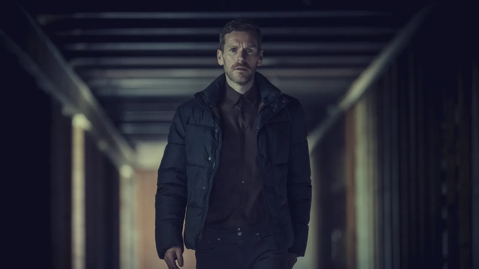 Group of colleagues gathered around a conference table looking at a laptop in an office meeting room