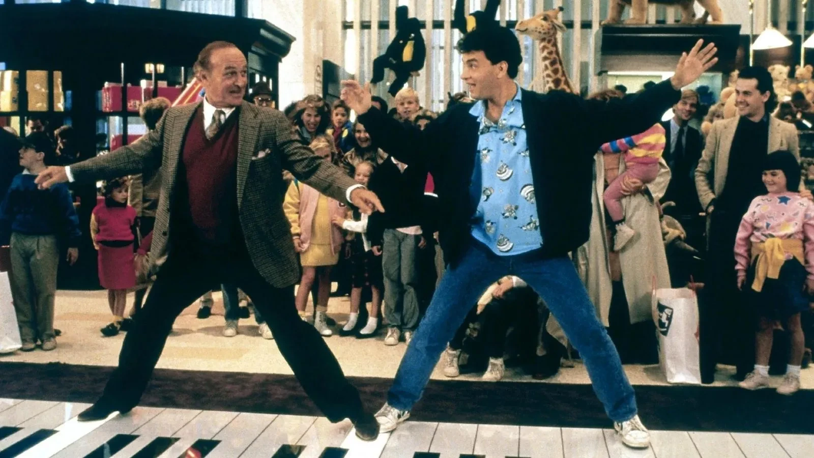 Scene inside a toy store featuring two people playing a giant floor piano, surrounded by children and shoppers, with large stuffed animals and shelves of toys in the background.