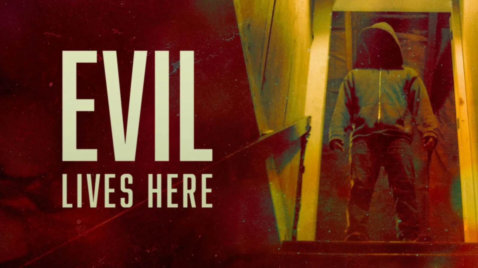 A dimly lit staircase leads down to a figure in a hooded sweatshirt standing in shadow. Large text on the left reads “EVIL LIVES HERE” in bold letters.